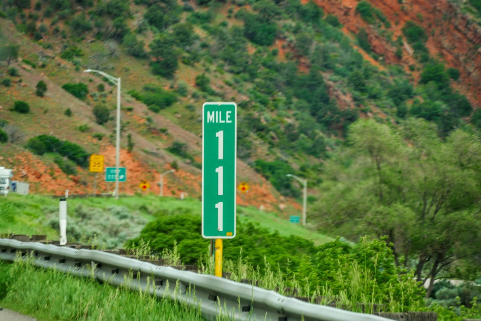 A highway mile marker beside the guardrail
