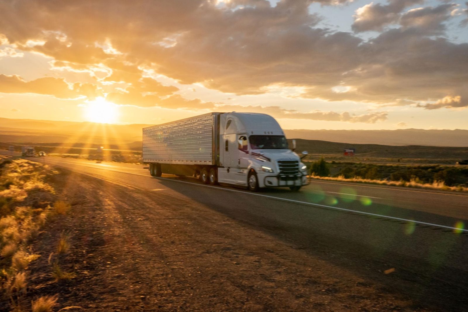A tractor-trailer on the highway at sunset
